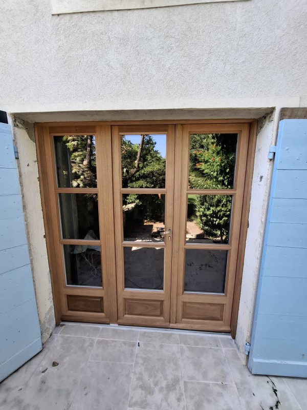 Fabrication et pose d'une porte fenêtre 3 vantaux dont un fixe en bois exotique rouge pour une maison à Cadenet